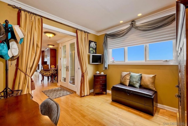 living area featuring french doors, crown molding, and light hardwood / wood-style floors