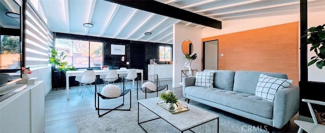 living room featuring vaulted ceiling with beams and light wood-type flooring