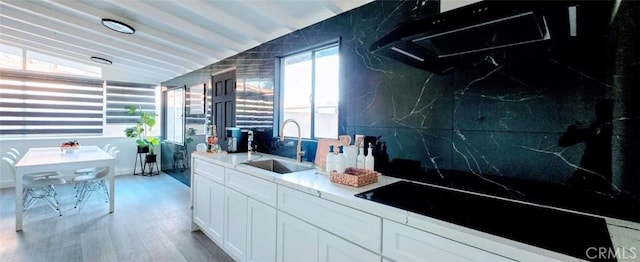 kitchen with sink, light hardwood / wood-style flooring, white cabinetry, tasteful backsplash, and vaulted ceiling