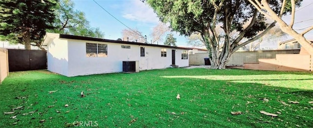 rear view of house featuring central AC unit and a lawn