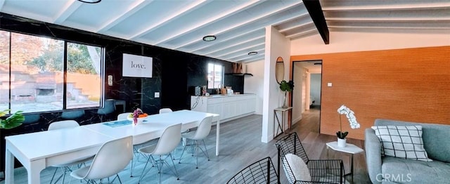 dining area featuring light hardwood / wood-style floors and vaulted ceiling with beams