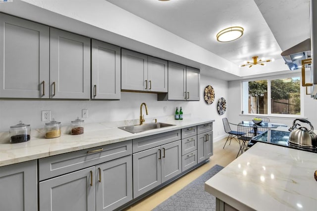 kitchen featuring gray cabinets, sink, and light stone countertops