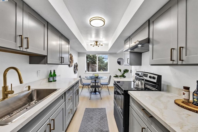 kitchen featuring sink, gray cabinets, light stone counters, a tray ceiling, and black range with electric cooktop