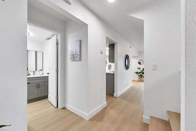 hall with sink and light wood-type flooring