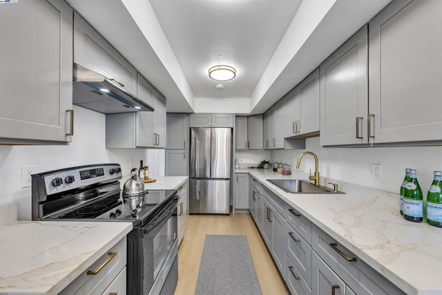 kitchen with gray cabinets, ventilation hood, sink, stainless steel appliances, and light wood-type flooring