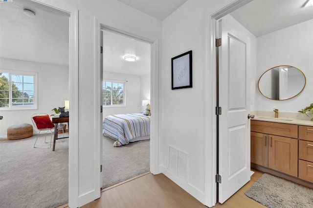 hall with sink and light carpet