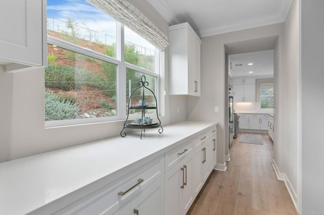 kitchen featuring crown molding, white cabinets, and light hardwood / wood-style flooring