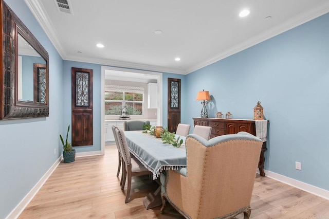 dining area featuring ornamental molding and light hardwood / wood-style flooring