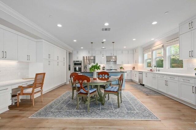 dining room featuring sink, built in desk, ornamental molding, and light hardwood / wood-style floors