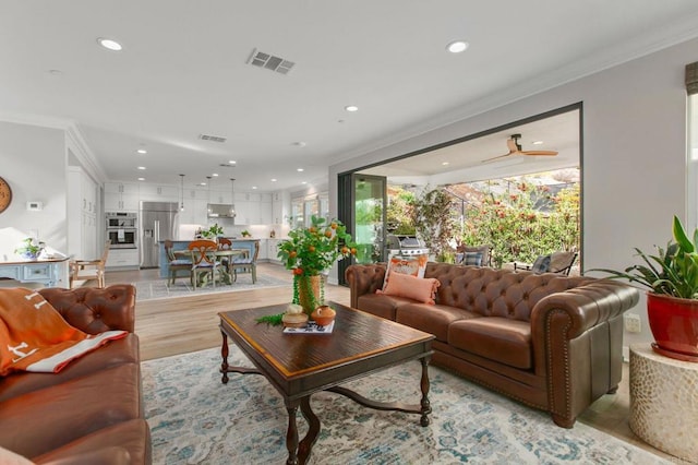 living room featuring ornamental molding and light hardwood / wood-style flooring