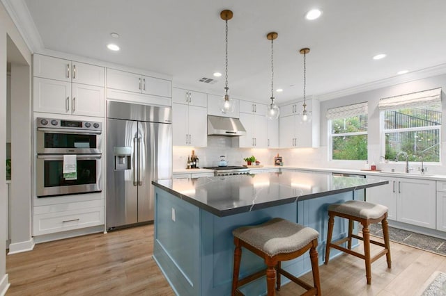 kitchen with stainless steel appliances, white cabinetry, a center island, and a kitchen breakfast bar