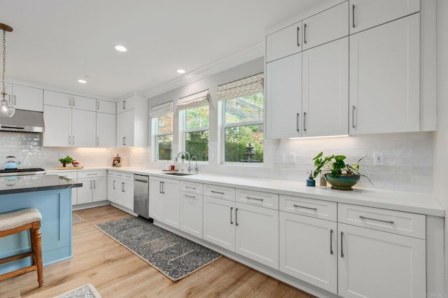 kitchen with sink, white cabinets, hanging light fixtures, exhaust hood, and light wood-type flooring