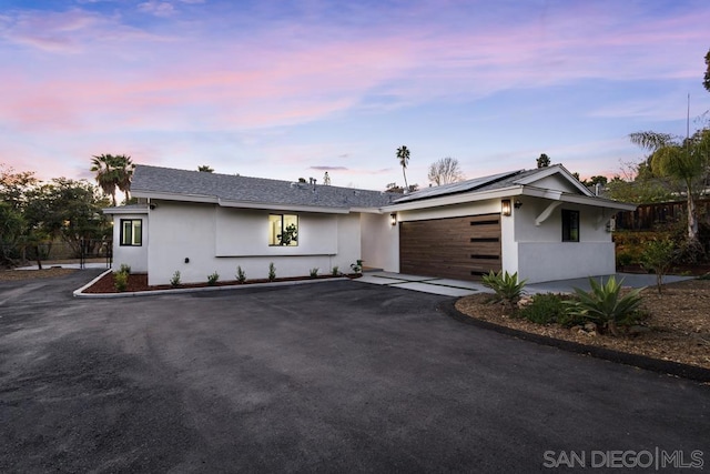 single story home with a garage and solar panels