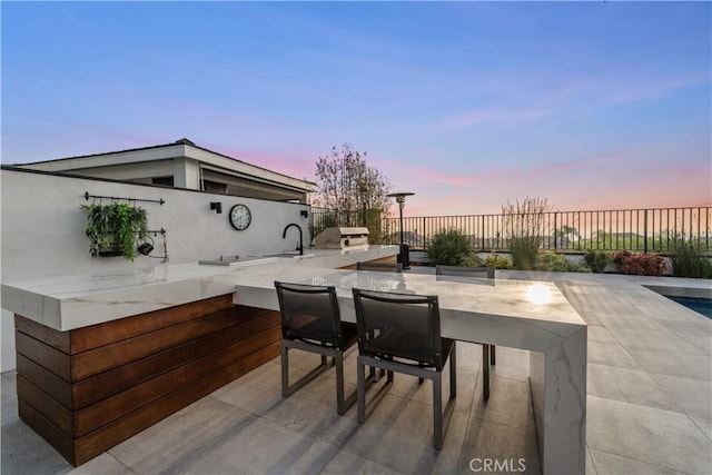 patio terrace at dusk featuring exterior kitchen and exterior bar