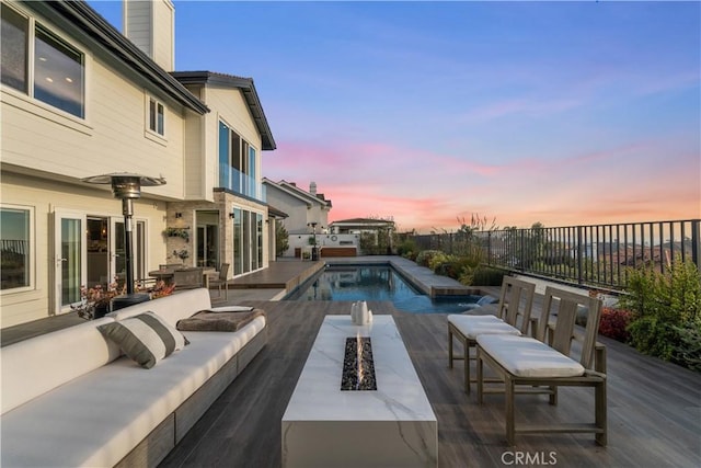 pool at dusk with a patio area and an outdoor living space with a fire pit