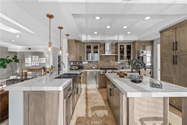 kitchen featuring a raised ceiling, a spacious island, hanging light fixtures, and wall chimney exhaust hood