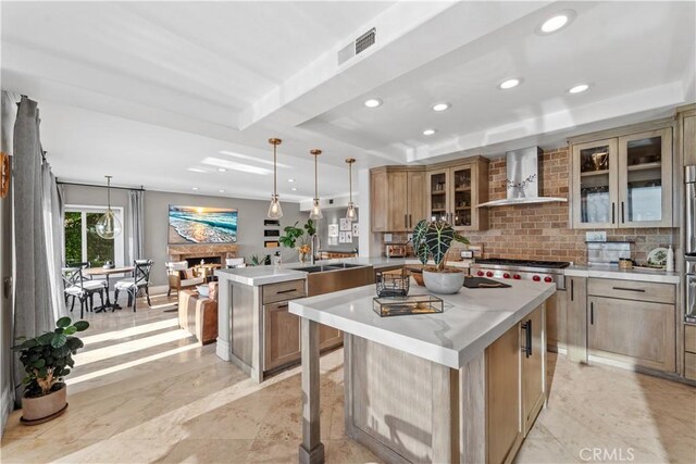 kitchen with a large island, hanging light fixtures, and wall chimney range hood