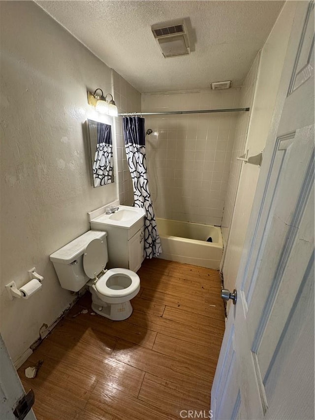 full bathroom featuring toilet, wood-type flooring, shower / tub combo, a textured ceiling, and vanity