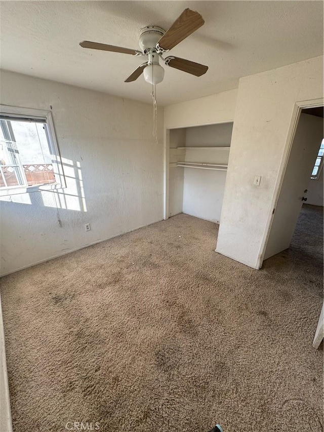 unfurnished bedroom featuring a textured ceiling, carpet floors, a closet, and ceiling fan