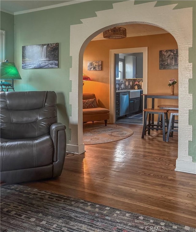 living room featuring arched walkways, wood finished floors, and ornamental molding