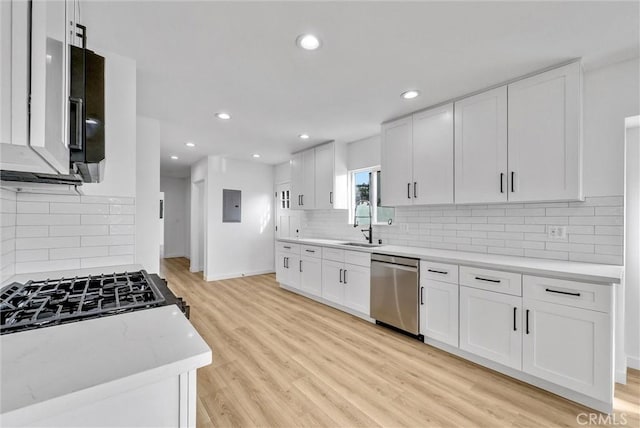 kitchen featuring white cabinetry, sink, stainless steel dishwasher, electric panel, and light hardwood / wood-style flooring