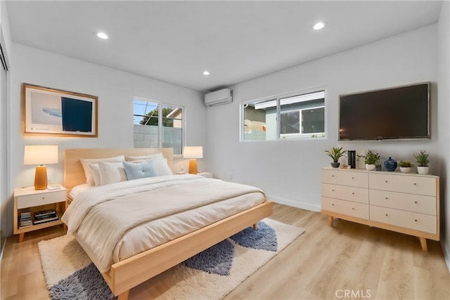 bedroom featuring an AC wall unit and light hardwood / wood-style flooring