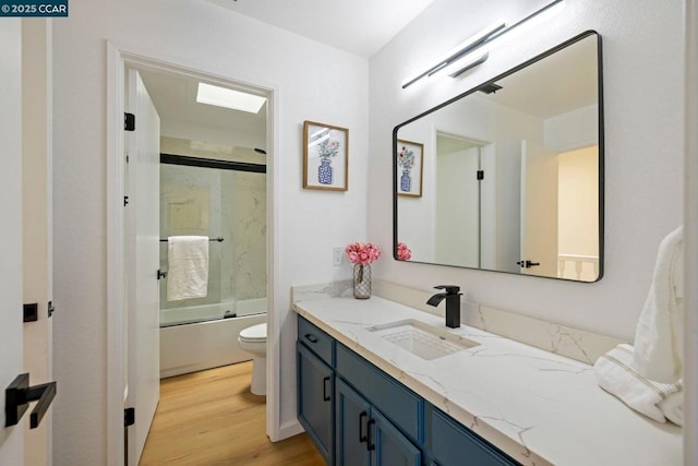 full bathroom featuring vanity, hardwood / wood-style floors, shower / bath combination with glass door, and toilet