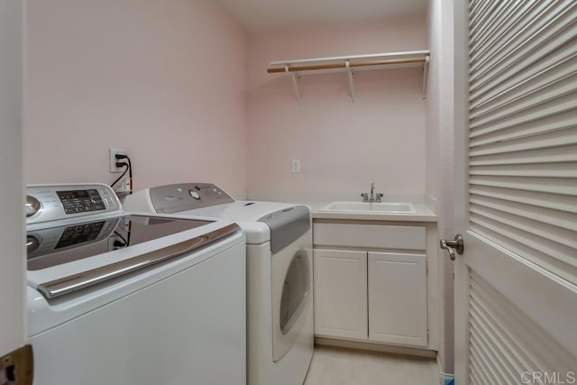 clothes washing area with cabinets, washing machine and clothes dryer, and sink