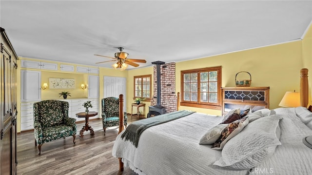 bedroom featuring hardwood / wood-style flooring, ceiling fan, and a wood stove