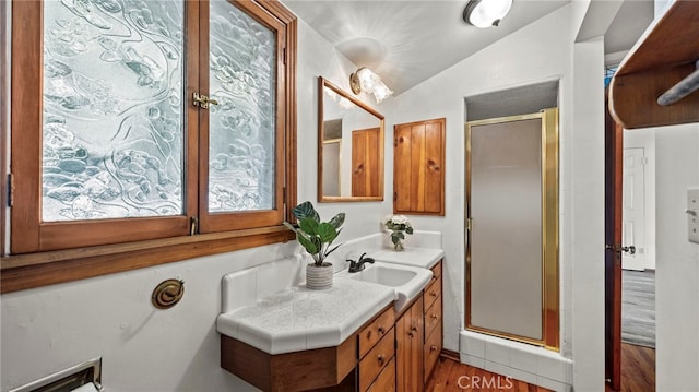 bathroom featuring vanity, hardwood / wood-style flooring, vaulted ceiling, and a shower with door