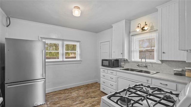 kitchen featuring stainless steel refrigerator, tasteful backsplash, white cabinetry, sink, and white range with gas cooktop