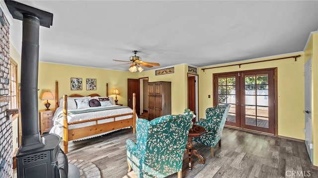 bedroom with hardwood / wood-style flooring, a wood stove, access to outside, and french doors