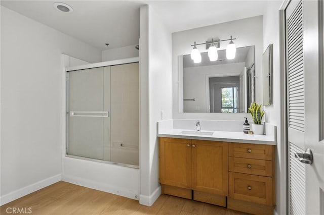 bathroom featuring vanity, hardwood / wood-style floors, and combined bath / shower with glass door