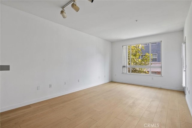 spare room with rail lighting and light hardwood / wood-style floors