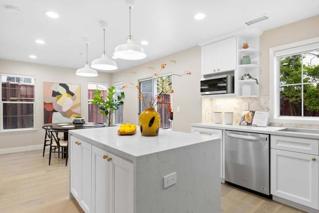 kitchen with a center island, appliances with stainless steel finishes, pendant lighting, decorative backsplash, and white cabinets