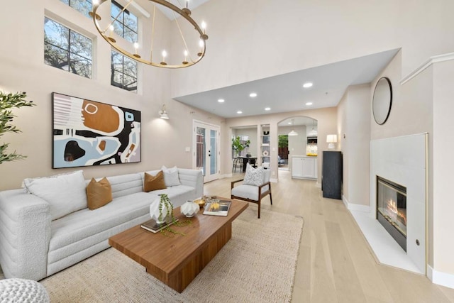 living room with light hardwood / wood-style floors, a chandelier, and a high ceiling