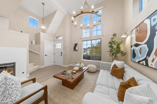 living room with a towering ceiling, light hardwood / wood-style flooring, and a notable chandelier