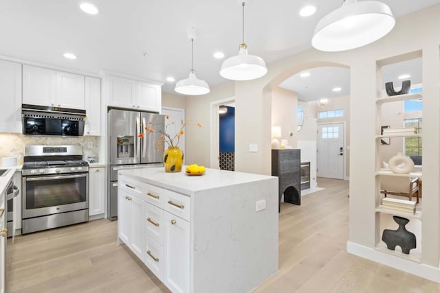 kitchen featuring appliances with stainless steel finishes, a center island, tasteful backsplash, white cabinets, and decorative light fixtures