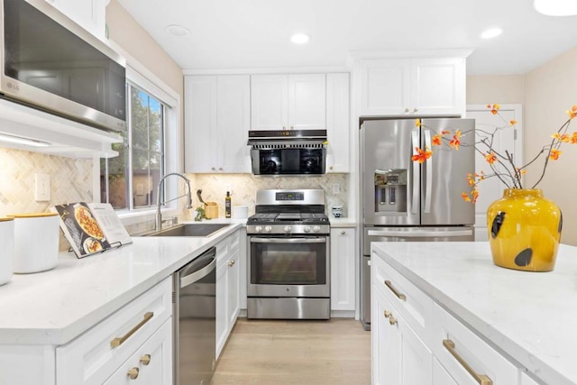 kitchen featuring sink, decorative backsplash, stainless steel appliances, and white cabinets