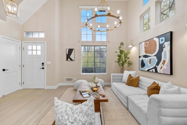 living room with a high ceiling, a notable chandelier, and light hardwood / wood-style floors