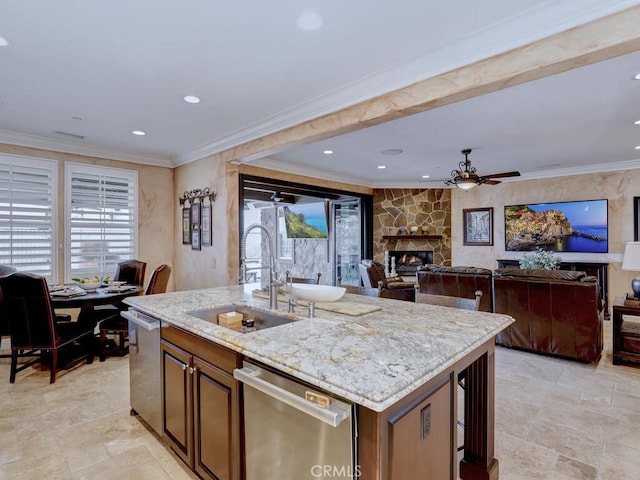 kitchen featuring sink, ornamental molding, a kitchen island with sink, stainless steel dishwasher, and light stone counters