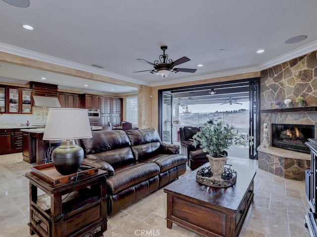 living room featuring crown molding, a stone fireplace, and ceiling fan