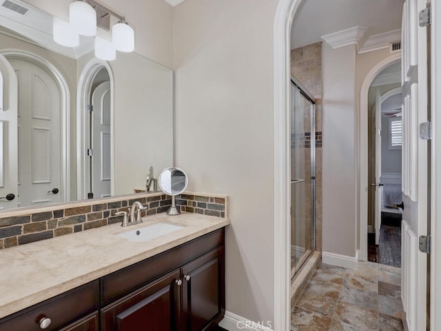 bathroom with tasteful backsplash, ornamental molding, vanity, and a shower with shower door