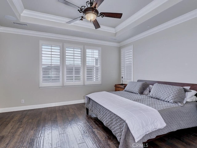 bedroom with ornamental molding, dark hardwood / wood-style floors, ceiling fan, and a tray ceiling