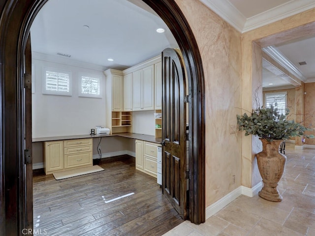 home office featuring light hardwood / wood-style flooring, built in desk, and ornamental molding