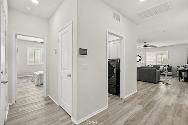 hall with visible vents, light wood-style floors, and washer / dryer