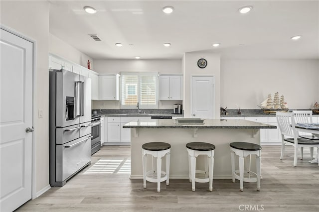 kitchen with visible vents, a breakfast bar, a sink, appliances with stainless steel finishes, and white cabinetry