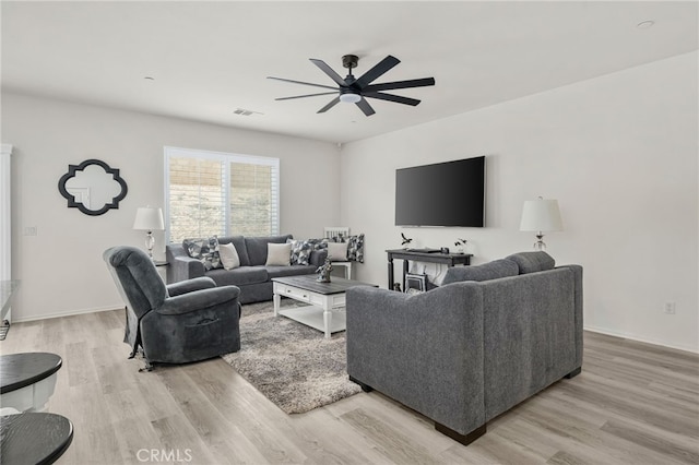 living room with light wood finished floors, visible vents, baseboards, and a ceiling fan