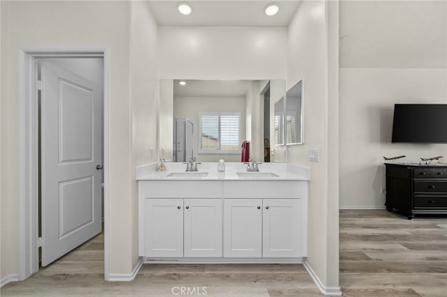 full bath with vanity, wood finished floors, and baseboards