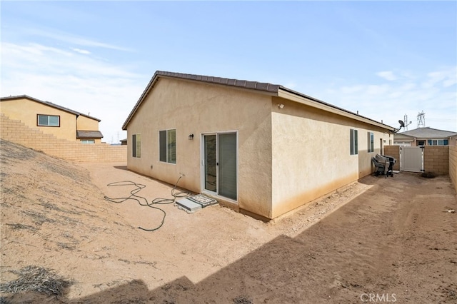 rear view of house with stucco siding and fence